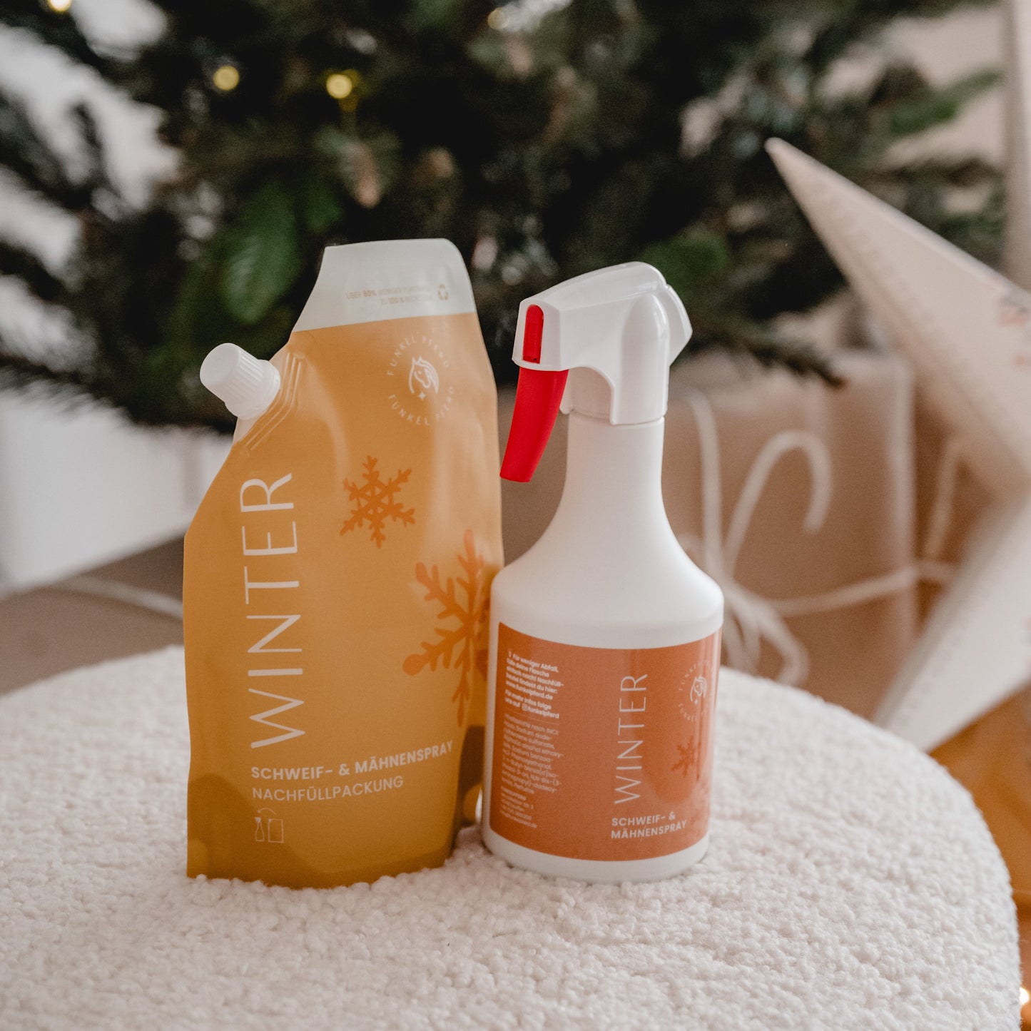 Winter Fellpflege Set bestehend aus Schweif- und Mähnenspray Sprühflasche und Nachfüllbeutel vor einem Weihnachtsbaum